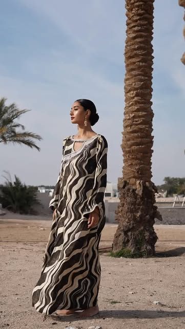 Model in a printed abaya beside a palm tree