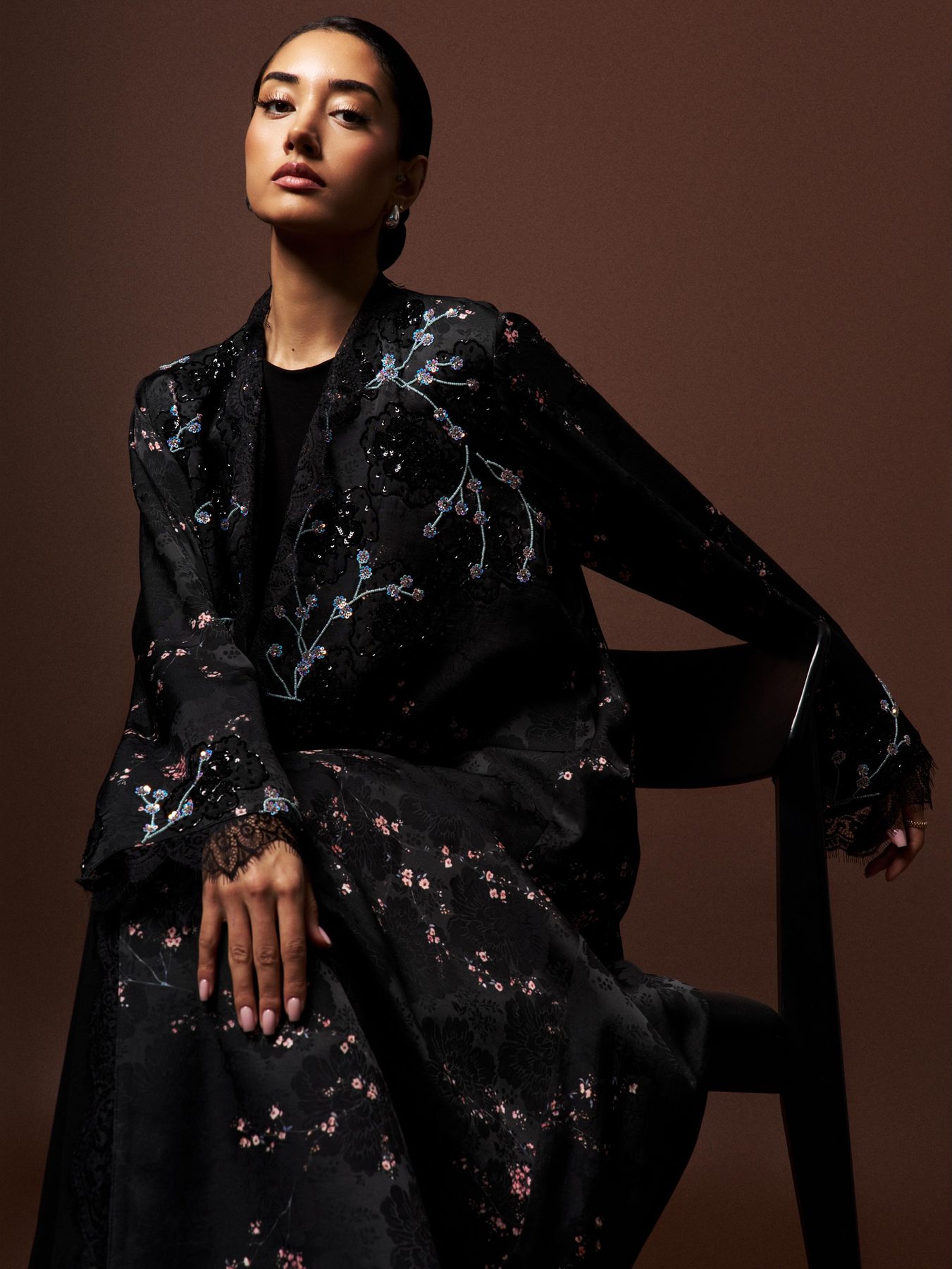 Model seated in the Sakura Noir abaya, black with cherry blossom embroidery